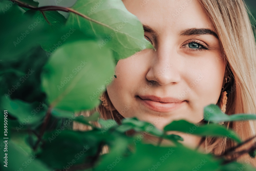 Portrait of a beautiful blonde girl with natural beauty in a green leaves trees. Copy, empty space for text Portrait of a beautiful blonde girl with natural beauty in a green leaves trees. Copy, empty space for text