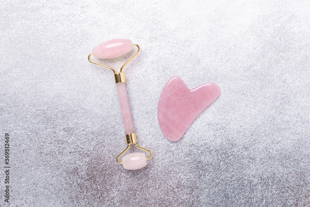 Gua Sha massager and face roller on stone background. Massage tool for facial skin care, SPA beauty treatment concept. Horizontal banner Gua Sha massager and face roller on stone background. Massage tool for facial skin care, SPA beauty treatment concept. Horizontal banner