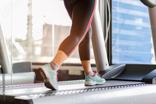 Close up foot sneakers Fitness girl running on track treadmill, Fat woman with muscular legs in exercise gym.