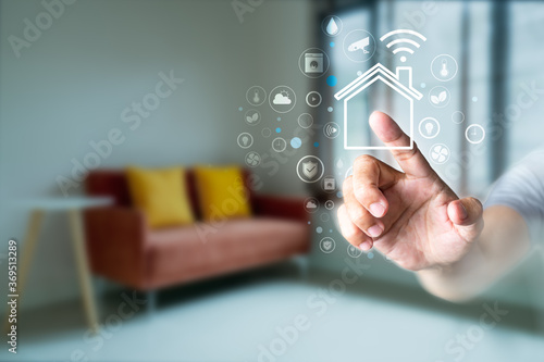 Man's finger touching the icons of smart home application on virtual screen with blurred room background. Home automation Concept photo