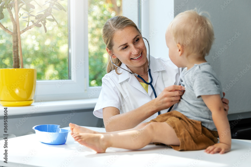 Child Doctor doctor examining a child patient by stethoscope in clinic office ...