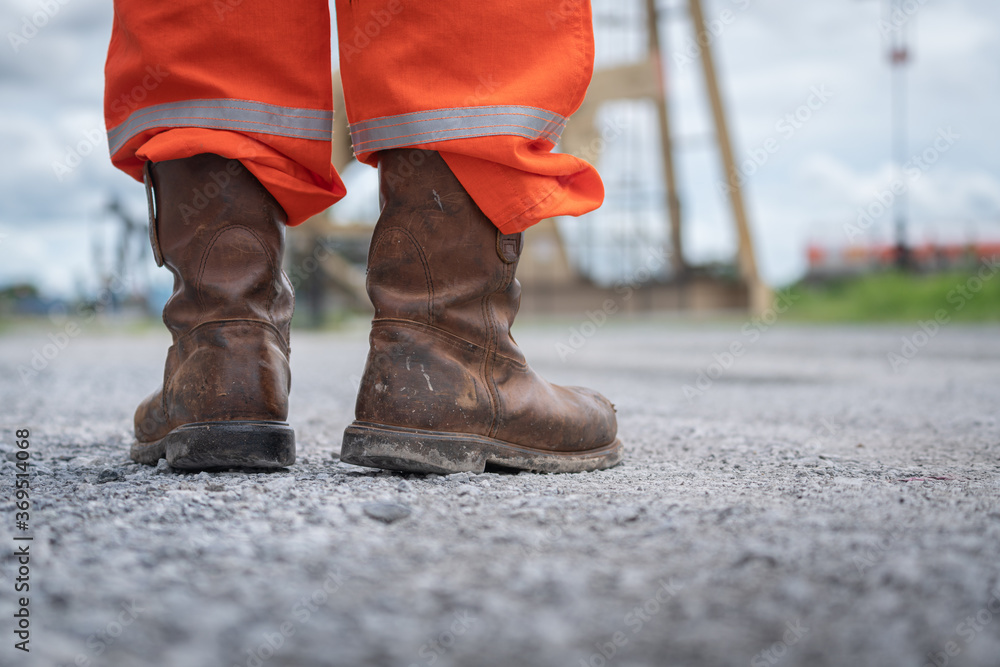 Close-up at Oil field operator's safety boots part with background of  outdoor site location. Working in dangerous industrial or business concept  action photo. Stock Photo | Adobe Stock