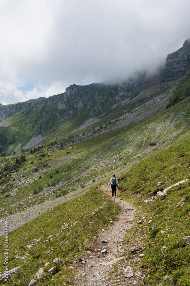 Woman with backpack, hiking in the swiss alps canton of Glarus, Switzerland, vertical