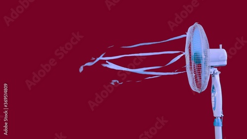Footage of a home appliance using for avoiding swelter and overheating, blowing fresh and cool wind, decorating with ribbons.Studio shot on red background.Equipment,comfort,technology concept.