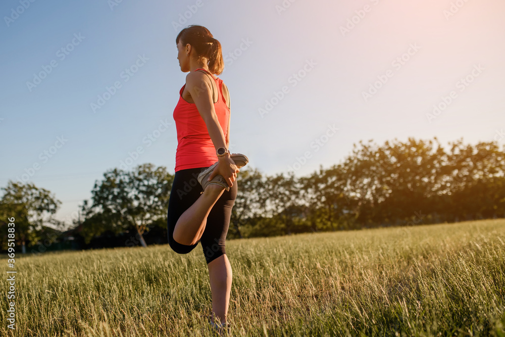 Young beautiful woman is making sport, she is doing the legs exercises on a grass in the midst of nature on sunset and preparing for running. Young beautiful woman is making sport, she is doing the legs exercises on a grass in the midst of nature on sunset and preparing for running.