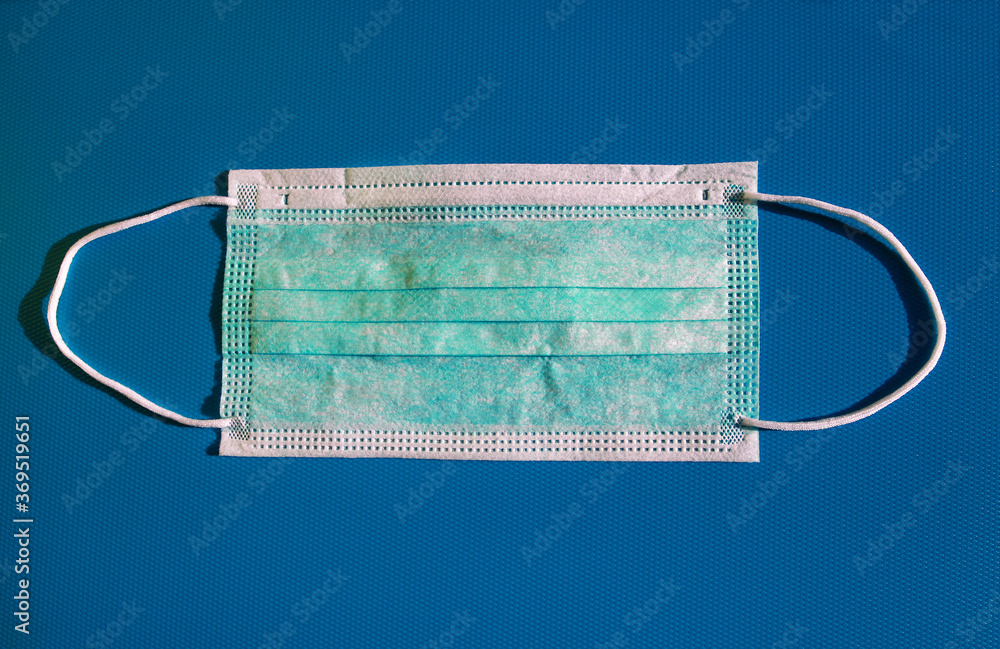 Medical protective green mask activated carbon disposable fiber face on blue background. Face mask that covers mouth and nose, that protects against virus, flu, coronavirus (COVID-19) and bacterial. Medical protective green mask activated carbon disposable fiber face on blue background. Face mask that covers mouth and nose, that protects against virus, flu, coronavirus (COVID-19) and bacterial.