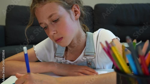 Young schoolgirl drawing eye at home.