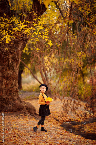 girl with yellow leaves in hands in an autumn Park