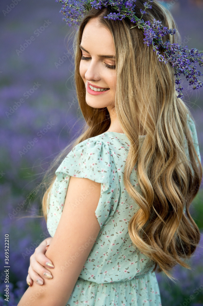 Naklejka premium Beautiful girl in lavender wreath and retro dress on the lavender field. Beautiful woman in the lavender field on sunset in France .Girl collect lavender.Soft focus. Series.