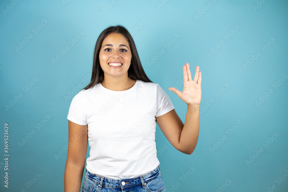 Fototapeta premium Young beautiful woman over isolated blue background doing star trek freak symbol