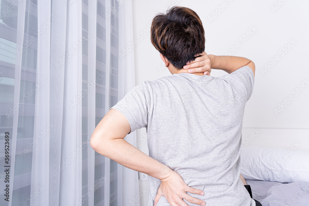 Young man suffering neck and back pain from uncomfortable bed. Healthcare medical or daily life concept. Young man suffering neck and back pain from uncomfortable bed. Healthcare medical or daily life concept.