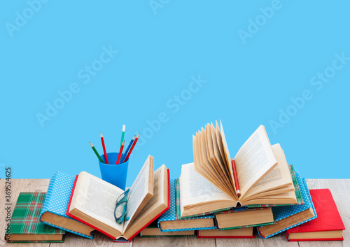 Back to school, pile of books in colorful covers and on wooden table with empty blue background. Distance home education.Quarantine concept of stay home