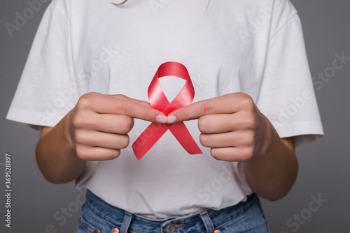 World Breast Cancer Day Concept. Health care woman wore white t-shirt with red ribbon for awareness. Symbolic bow color raising on people living with women's breast tumor illness