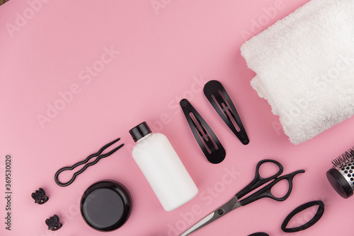 Professional hair dresser tools with copy space. Hair stylist equipment set on pink background. Scissors, brush, hairbrush, balm flat lay top view.