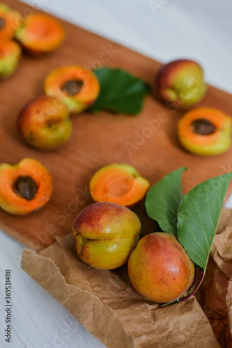 Raw fresh apricots laying on the wooden table with green leaf and knife