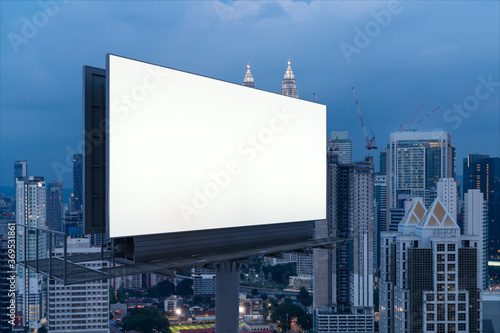 Blank white road billboard with KL cityscape background at night time. Street advertising poster  mock up  3D rendering. Side view. The concept of marketing communication to promote or sell idea.