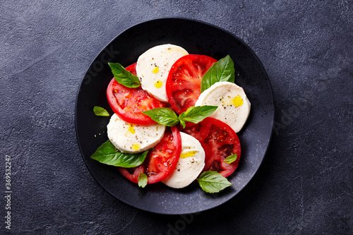 Caprese salad with tomatoes, mozzarella cheese, basil. Dark background. Close up. Top view. photo