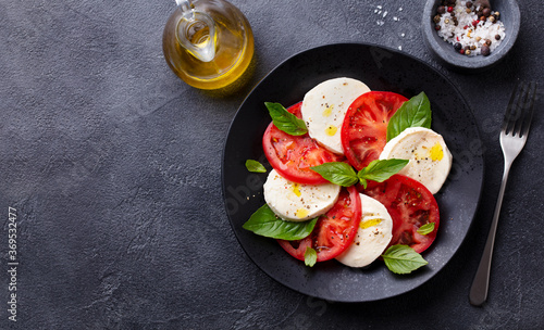 Caprese salad with tomatoes, mozzarella cheese, basil. Dark background. Copy space. Top view.