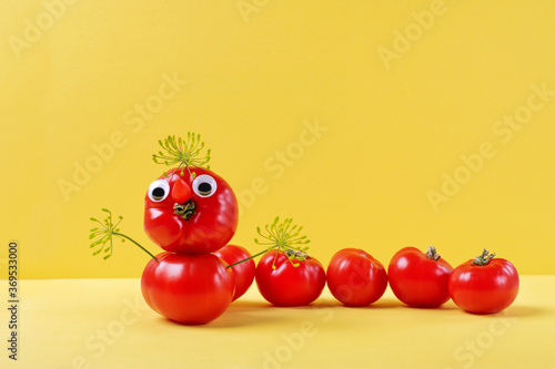 Funny caterpillar made of tomatoes against the yellow background. Cute food composition for kids menu