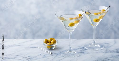 Martini cocktail with green olives on marble table background. Copy space. Close up.