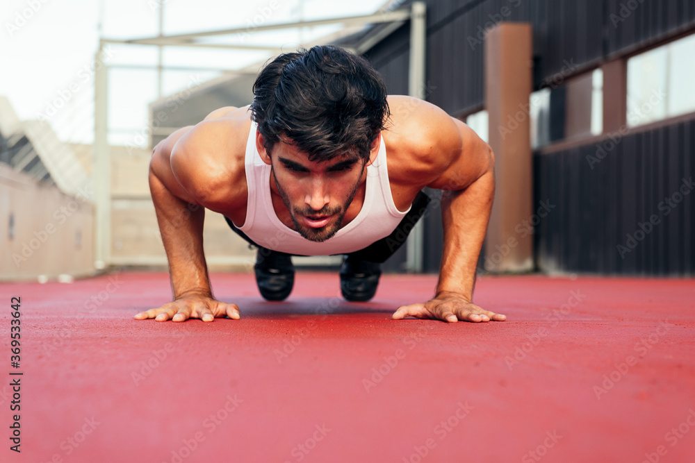 handsome sportsman doing push ups on a red floor handsome sportsman doing push ups on a red floor