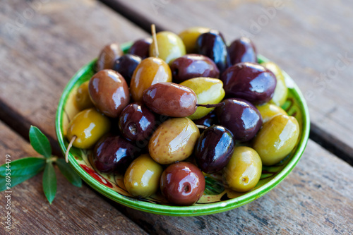 Assortment of fresh olives on a plate. Wooden background. Close up.