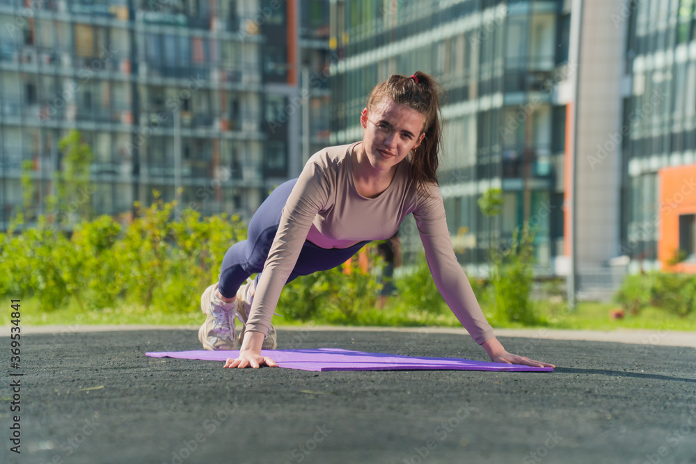 The girl on the rug is doing street training. Exercises for standing in the bar, push-ups show fitness trainer The girl on the rug is doing street training. Exercises for standing in the bar, push-ups show fitness trainer