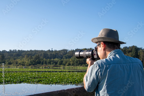 望遠レンズ付けた一眼レフカメラでネイチャ－フォト撮影をするサングラスをかけたアジア人男性 バンクーバー ブリティッシュコロンビア カナダ 