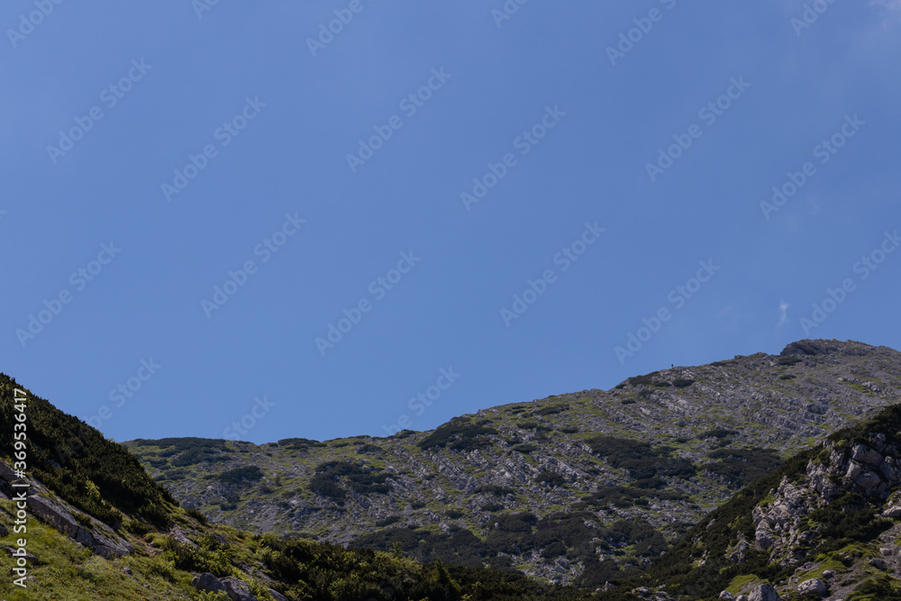 View of mountain top in European alps with small man walking on mountain ridge. View of mountain top in European alps with small man walking on mountain ridge.