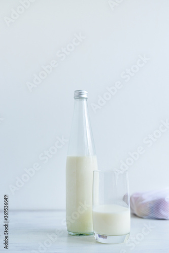Fresh milk on glass bottle standing on the white background with eggs and glass