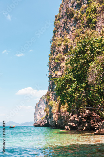 Landscape with a sheer cliff by the sea and a boat on a sunny day in Thailand