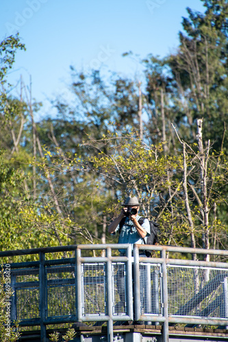 展望台から望遠レンズ付けた一眼レフカメラで写真撮影をするサングラスをかけたアジア人男性　　バンクーバー　ブリティッシュコロンビア　カナダ  © haseg77