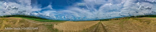 Panorama on some rural fields  with a blue sky and some clouds on it