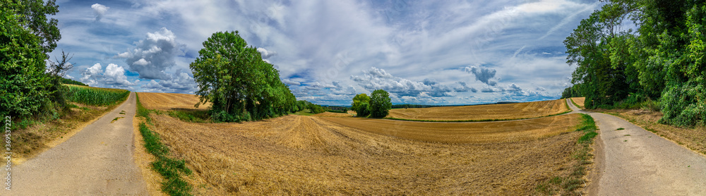 Panorama on some rural fields, with a blue sky and some clouds on it