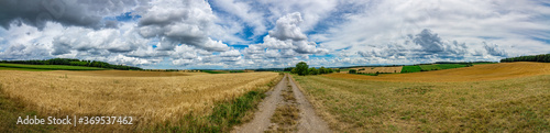 Panorama on some rural fields, with a blue sky and some clouds on it