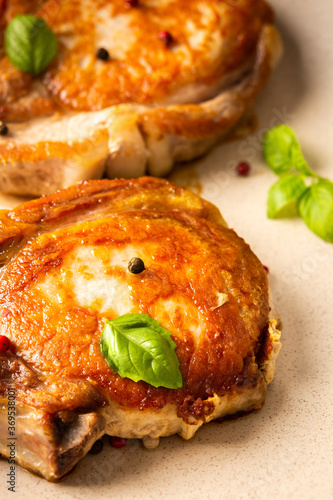 Fried pork entrecote on the bone, cooked pieces of pork meat with basil leaves and spices, steak on the bone in a plate