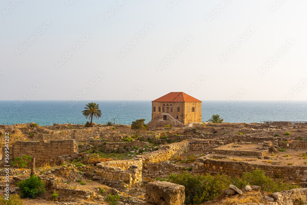 Excavation of Byblos, Lebanon. Traditional Lebanese house on the shores of the Mediterranean Sea. Seascape with blue water at sunset. Numerous stone walls of ancient structures