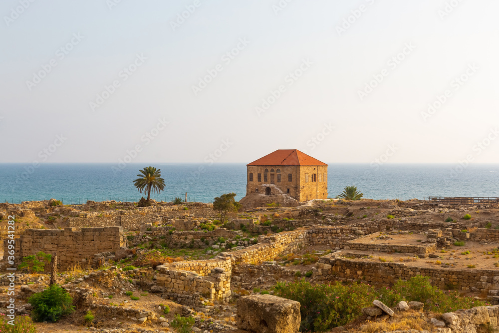 Excavation of Byblos, Lebanon. Traditional Lebanese house on the shores of the Mediterranean Sea. Seascape with blue water at sunset. Numerous stone walls of ancient structures Excavation of Byblos, Lebanon. Traditional Lebanese house on the shores of the Mediterranean Sea. Seascape with blue water at sunset. Numerous stone walls of ancient structures