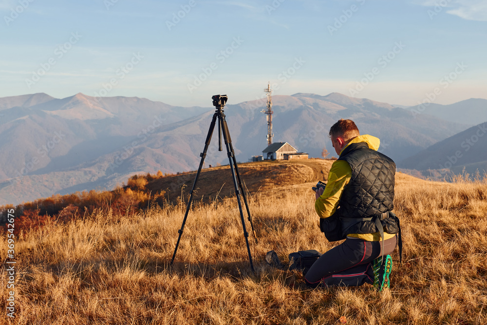 Male photographers standing and working at majestic landscape of autumn trees and mountains by the horizon