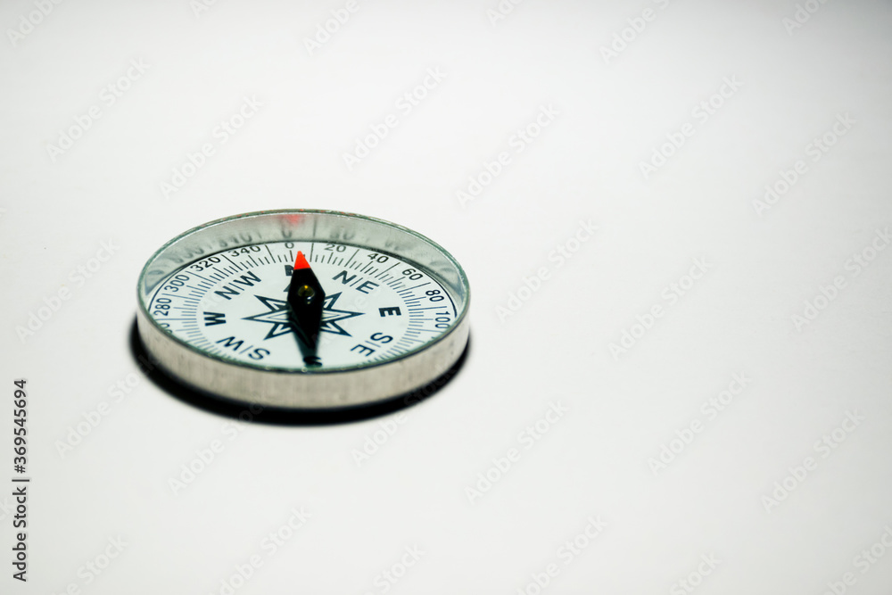A compass pointing North on a plain white background with empty space A compass pointing North on a plain white background with empty space