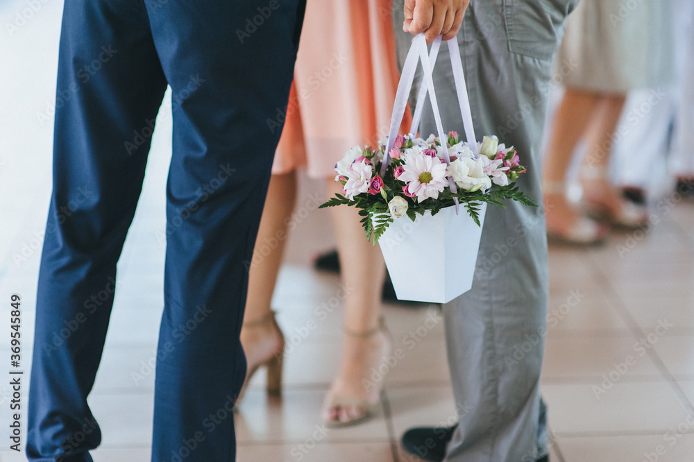 The guest at the wedding holds a basket of white paper with flowers, chrysanthemums. The guest at the wedding holds a basket of white paper with flowers, chrysanthemums.