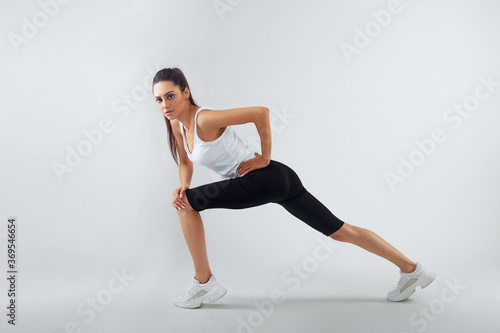 Fit woman stretching her leg to warm up - isolated over background