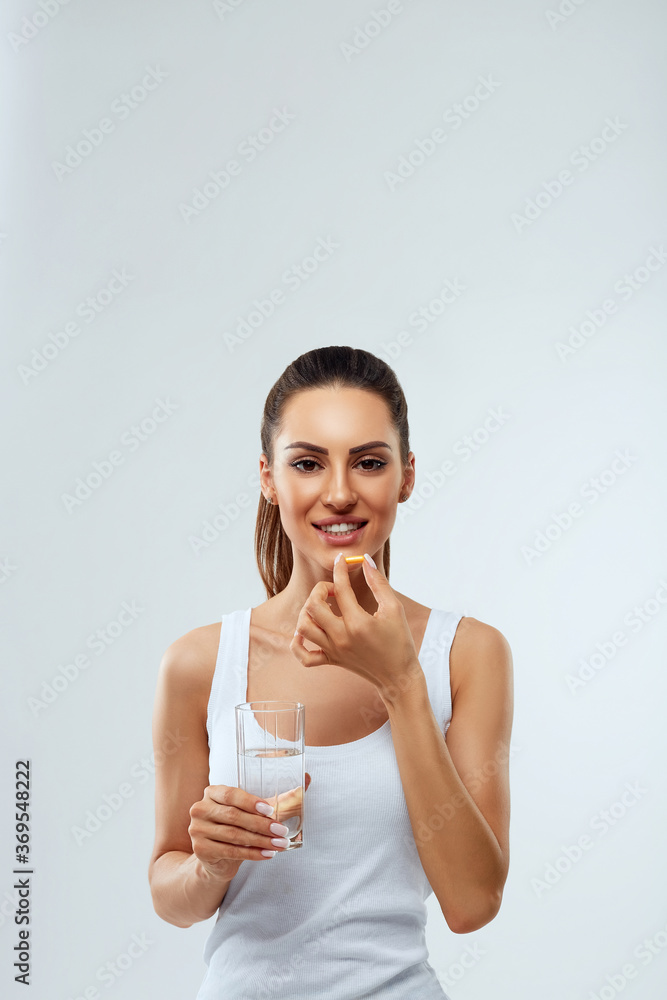 Happy Smiling Woman Taking Pill With Cod Liver Oil Omega-3 And Holding A Glass Of Fresh Water In Morning. Vitamin D, E, A Fish Oil Capsules. Diet. Nutrition. Healthy Eating Happy Smiling Woman Taking Pill With Cod Liver Oil Omega-3 And Holding A Glass Of Fresh Water In Morning. Vitamin D, E, A Fish Oil Capsules. Diet. Nutrition. Healthy Eating