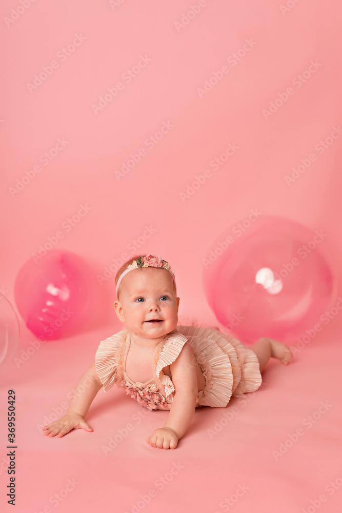 Happy baby girl on a pink background with balloons. Celebration. Birthday