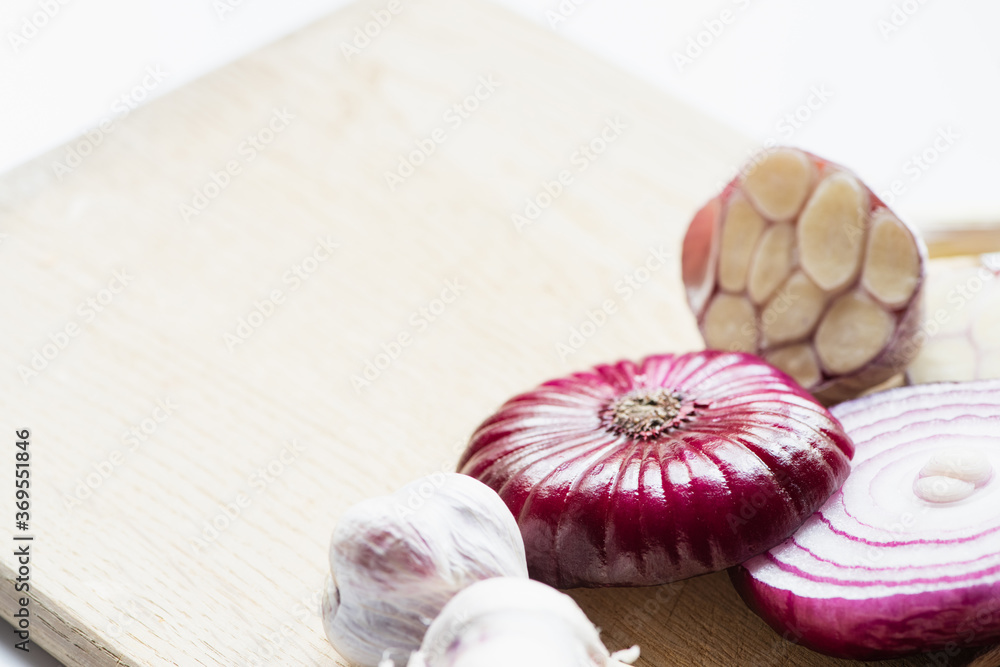 close up view of red onion and garlic on wooden cutting board isolated on white close up view of red onion and garlic on wooden cutting board isolated on white
