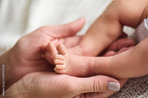 a mother holds the legs of her newborn baby in her hands. close up