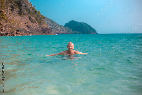 adult man swims in the sea against the background of mountains, summer sea holidays, travel and tourism.Vacation in Asia