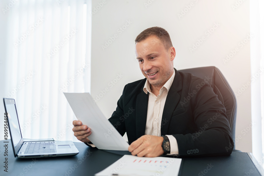 The businessman looks happily at the paper. The businessman looks happily at the paper.