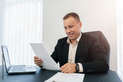 The businessman looks happily at the paper.