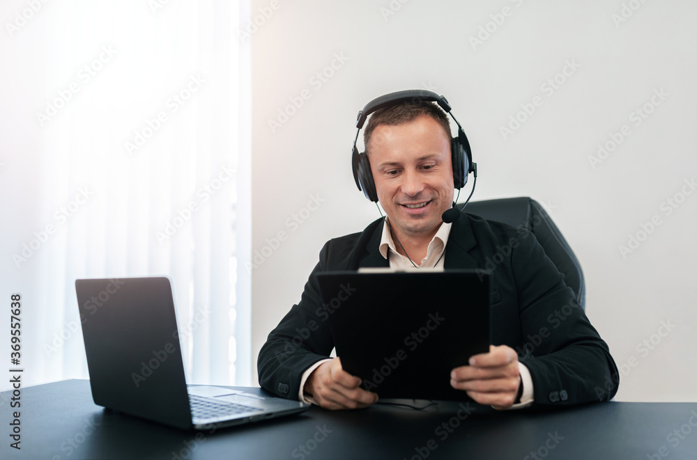 A man with headphones is working on a tablet. A man with headphones is working on a tablet.